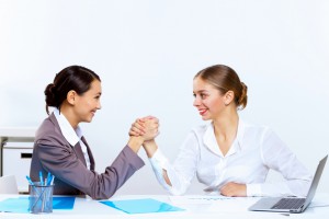 young women arm wrestling in office